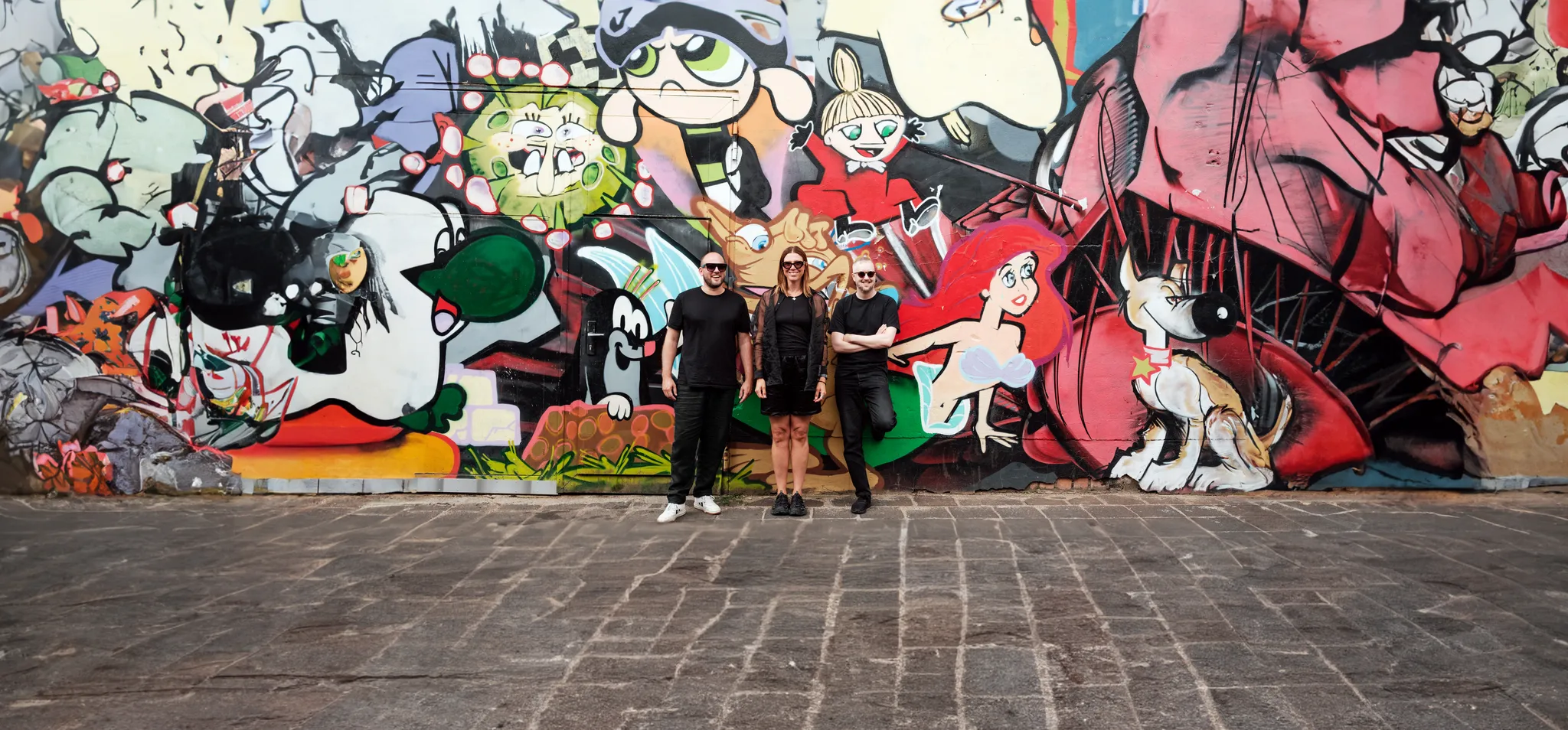 aeo team Anna Lundqvist, Eddy Salzmann and Ola Möller infront of a graffiti wall in Leipzig